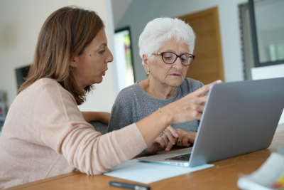 old woman using laptop with the help of her daughther