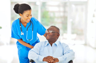 female caregiver with stethoscope looking to her old man patient sitting on the wheelchair