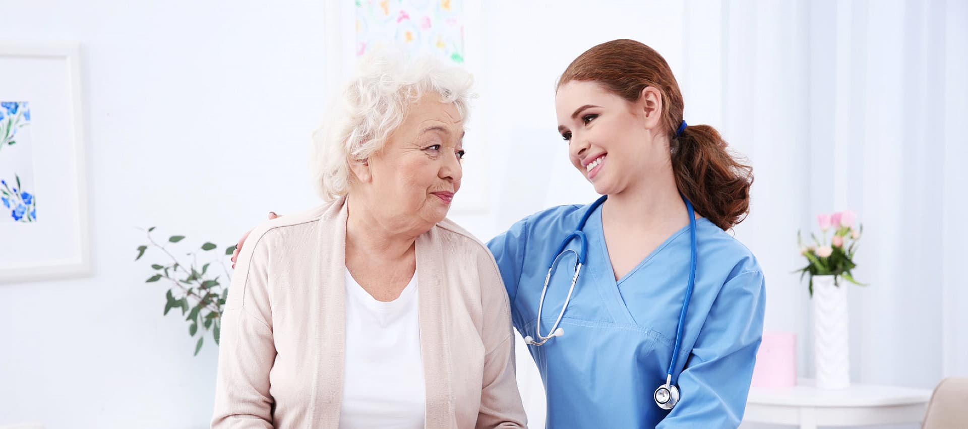 female caregiver with stethoscope with her old woman patient looking to each other