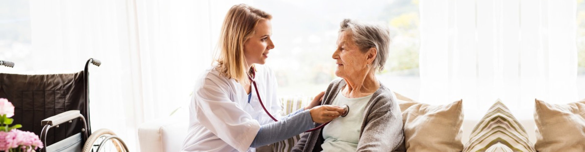 female caregiver checking the heart beat to her old woman patient